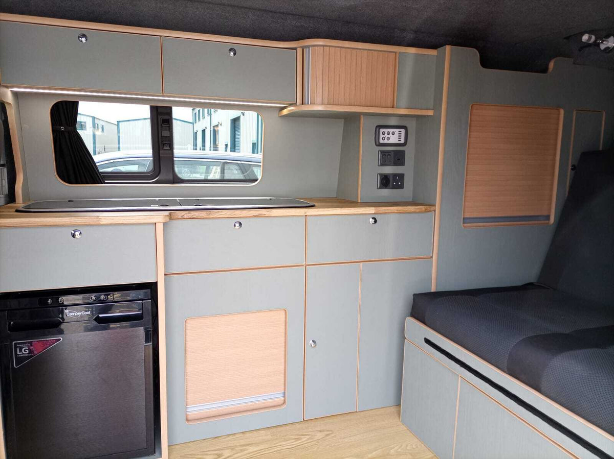 A black CamperCool fridge fitted under the worktop of a grey and oak kitchen unit